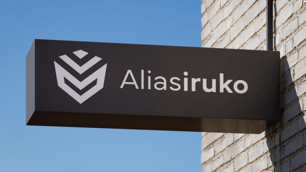 A close-up shot of a rectangular, dark gray sign mounted on a wall. The redesigned logo is visible in white.